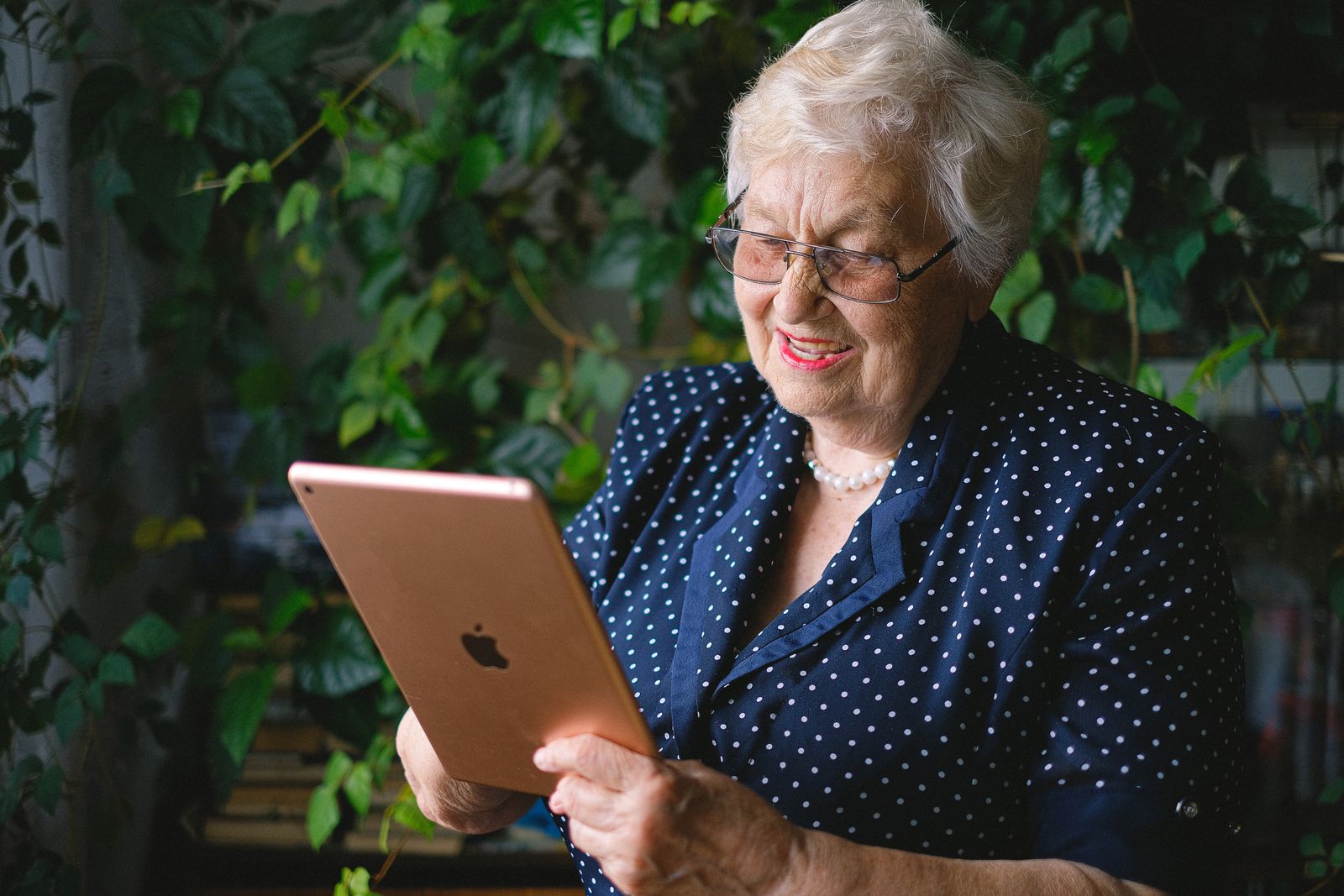 An older woman smiling at a tablet she is holding